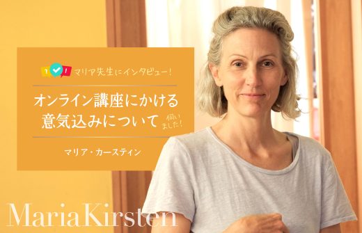 黄色い壁の前に立つマリア先生
