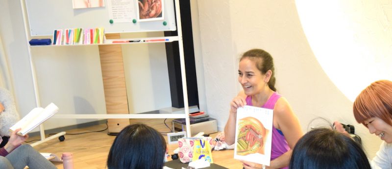 女性の体の仕組みを資料を見せながら笑顔で教えるキャシー