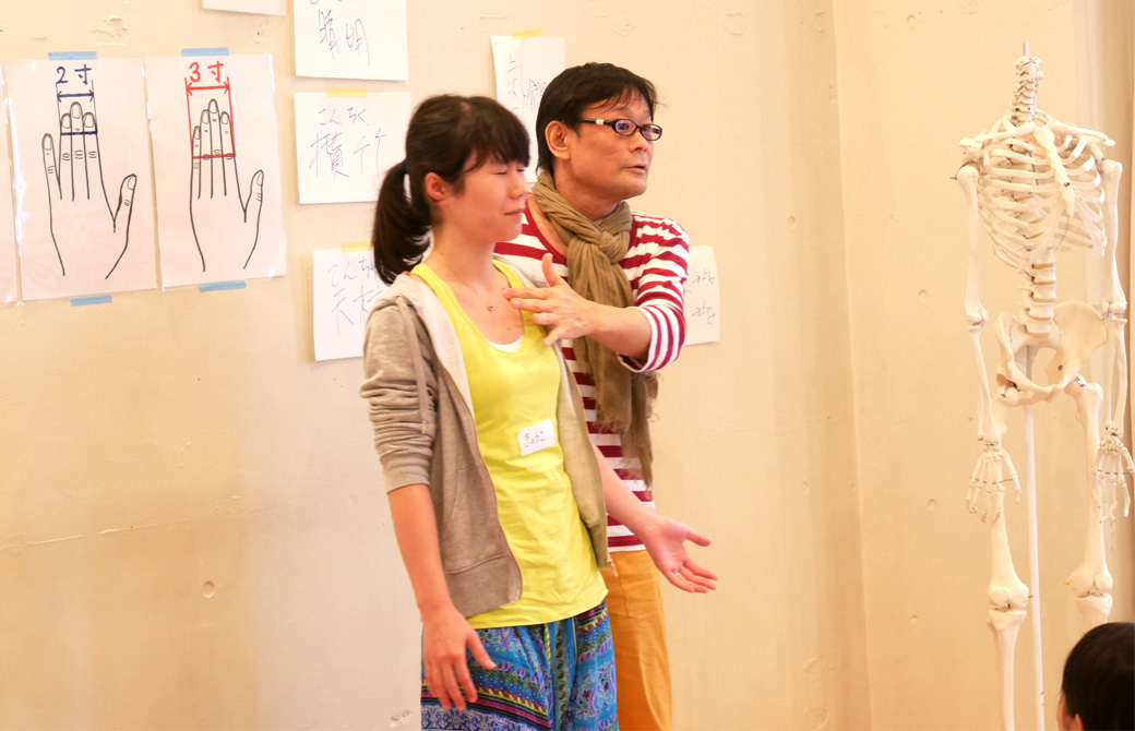 経絡(けいらく)基礎を学ぶ講座(3日間)の講座風景。講師(内田かつのり)が生徒の鎖骨付近のツボを刺激している様子