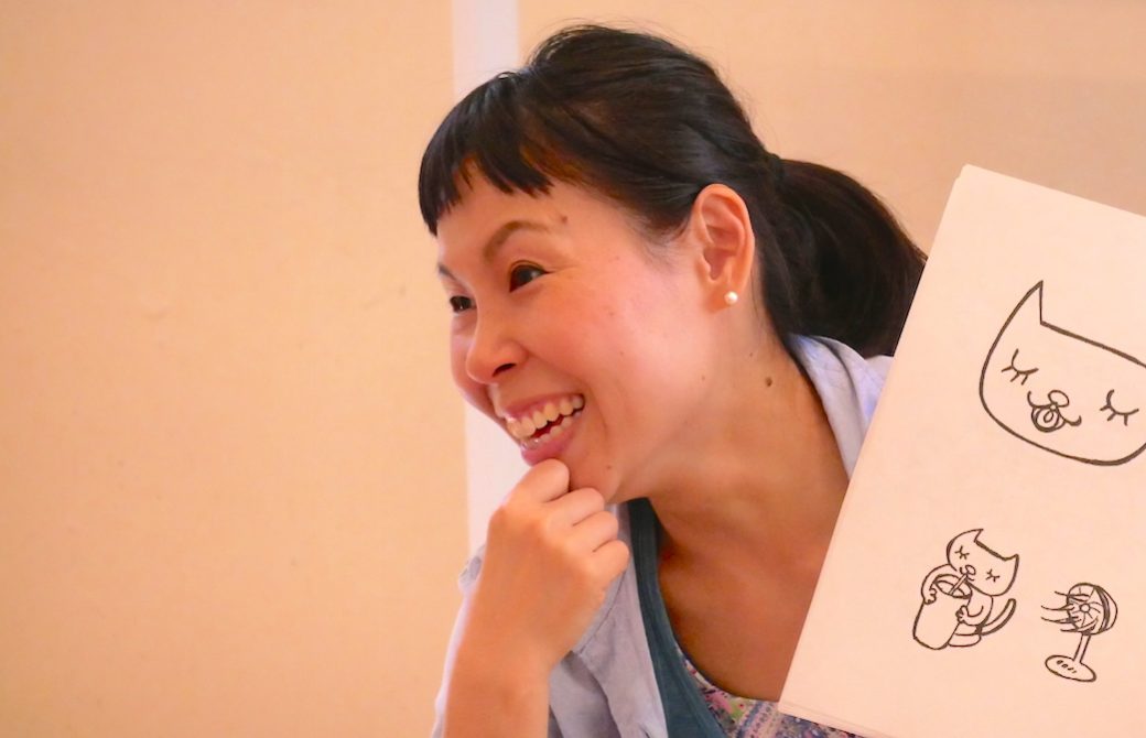 片岡まり子先生が絵本を持って笑っている