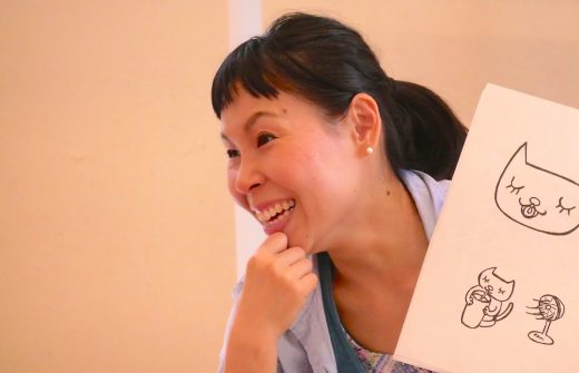 片岡まり子先生が絵本を持って笑っている
