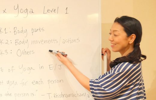 ホワイトボード前でヨガ英語の表現方法について説明している川原朋子先生