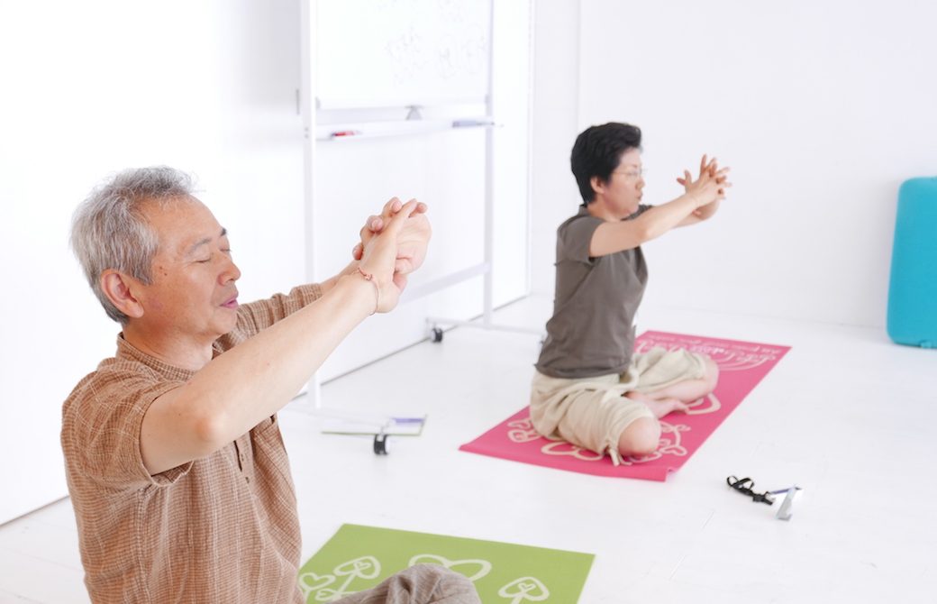 目をつむってヨガクラスをしている野口夫妻