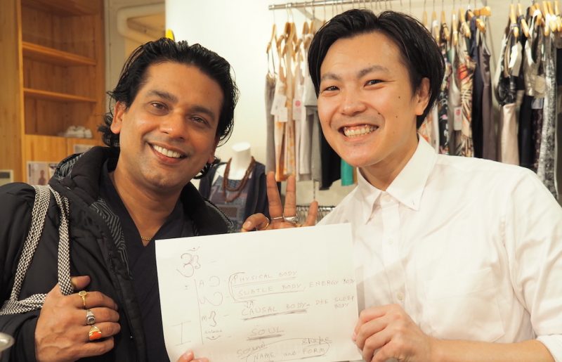 グルジ先生とぐっち先輩が笑顔で2ショット写真を撮っている、グッチ先輩の手にはオームのシンボルについて説明した内容が書かれている