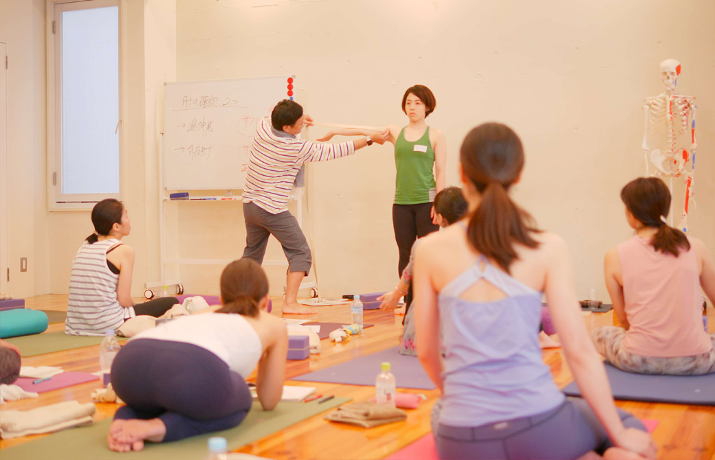 内田かつのり先生が生徒さんの広げた腕にベルトをあてて肘の過伸展をチェックしている様子