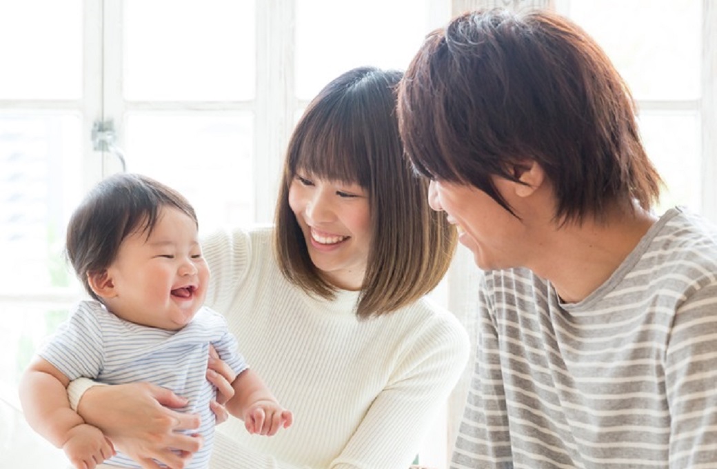 笑顔に赤ちゃんを抱っこしながら微笑むお母さんとお父さん