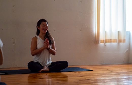 Maikokurata先生のクンダリーニヨガ90分クラスの様子。蓮華座で合掌して微笑んでいるMaiko先生