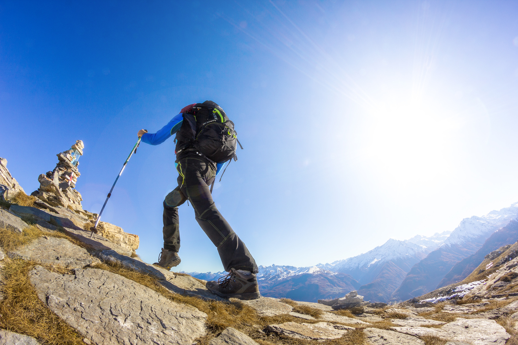 青空の下、登山をしている男性。