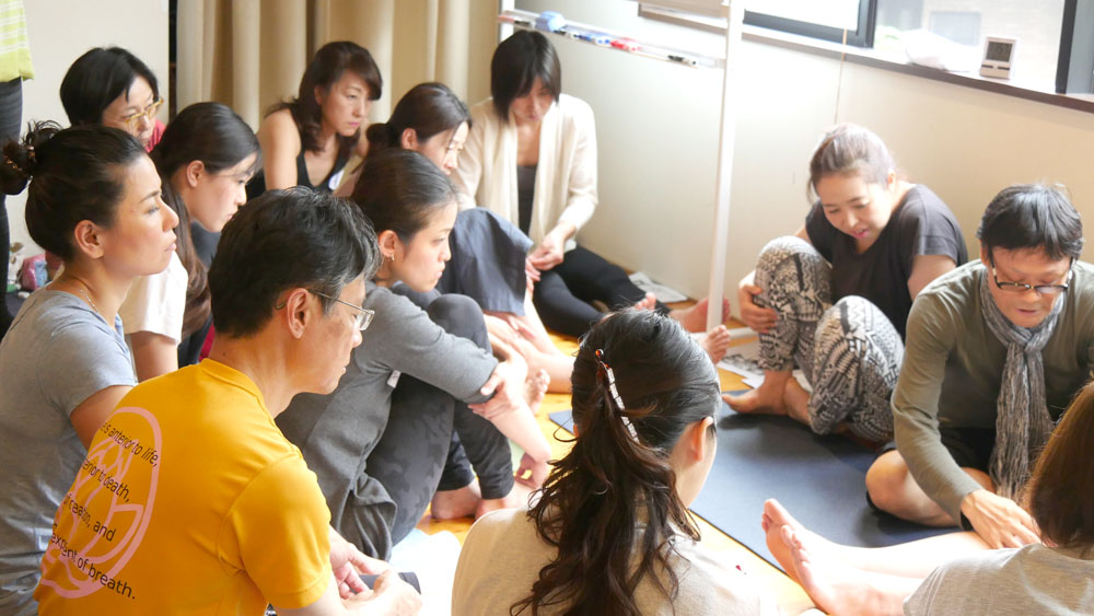 ヨガ解剖学講師内田かつのり先生による膝関節セラピーの様子。生徒さんを例にして、膝の怪我について説明する内田先生