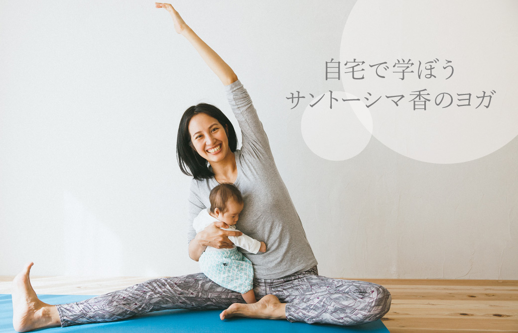 サントーシマ香先生がヨガマットの上で赤ちゃんを抱えてポーズを取っている