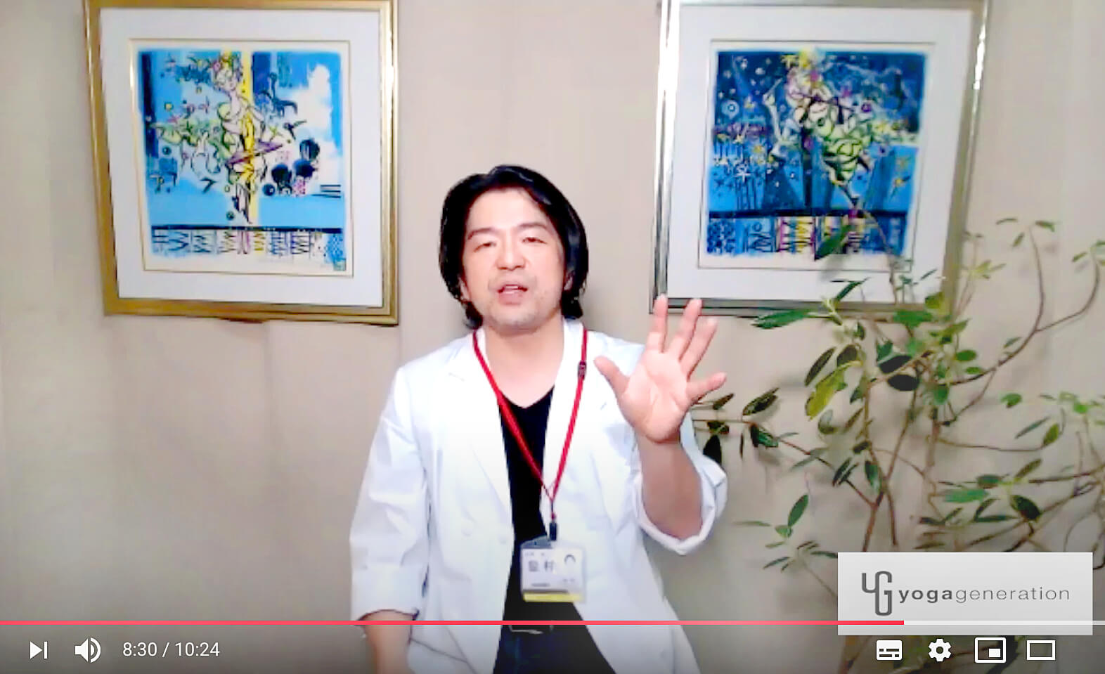 壁にかかる2枚の絵画の前で語る皇村先生