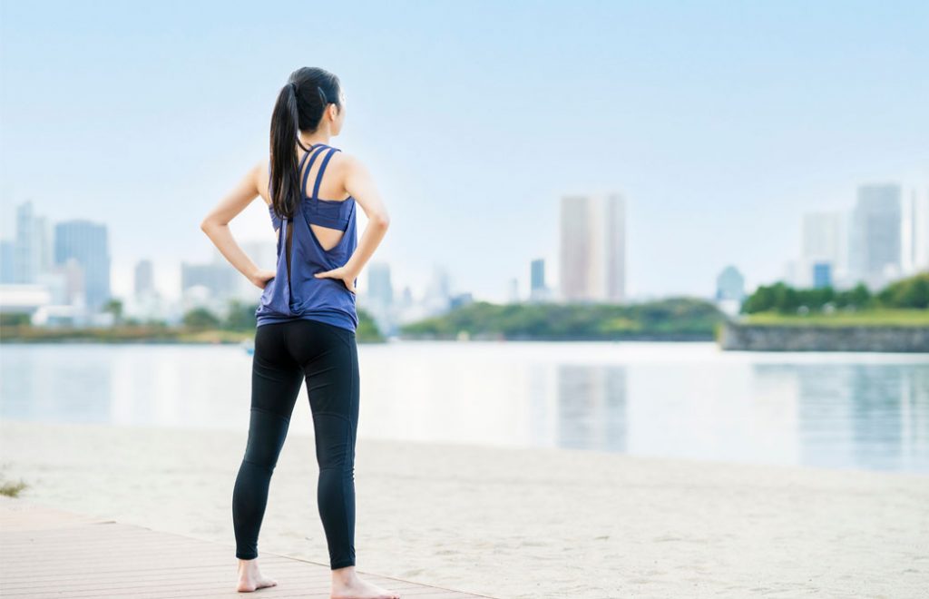 水辺に立つスポーツウェアを着た、髪を束ねた女性