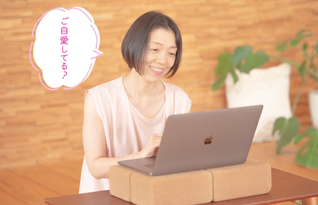 朋子先生がPCに向かってほほ笑んでいる