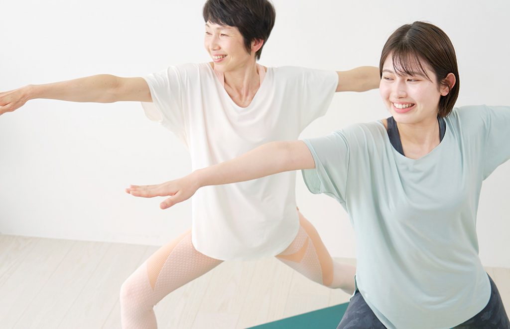 20代と50代の女性が戦士のポーズ2番を行なっている