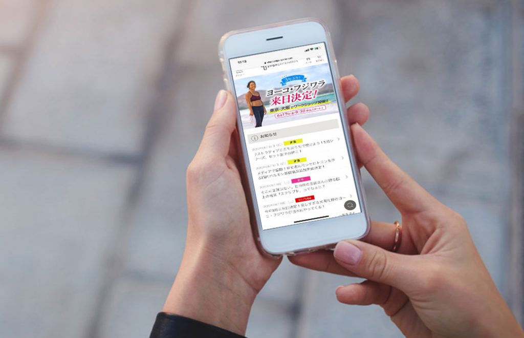 スマートフォンでヨガジェネレーション講座サイトを見ている