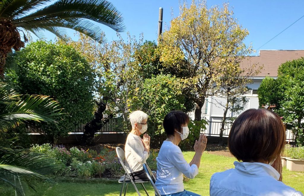 緑の芝の庭でチェアヨガをする3人の女性