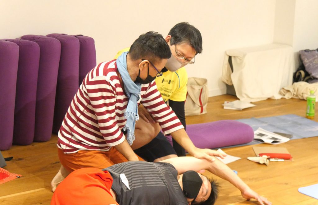 内田先生が、生徒さんの腕を挙げながら方を触っている。それを見ている他の生徒さん