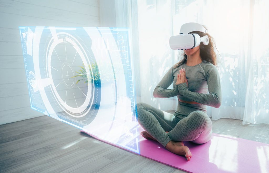 白いカーテンの引かれた窓際で、VRゴーグルをつけてヨガマットの上で座禅を組む女性