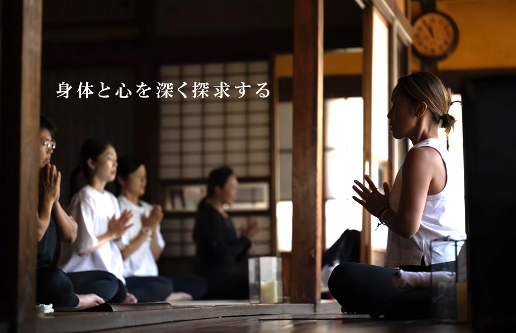 Maiko陰ヨガ_古い家屋で胡坐で座り手を合わせる講師Maikoと複数の生徒さん